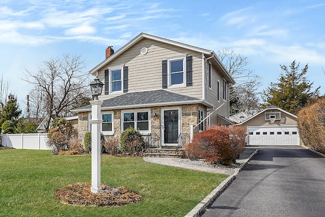 view of front of property with an outbuilding, stone siding, fence, a front yard, and a garage