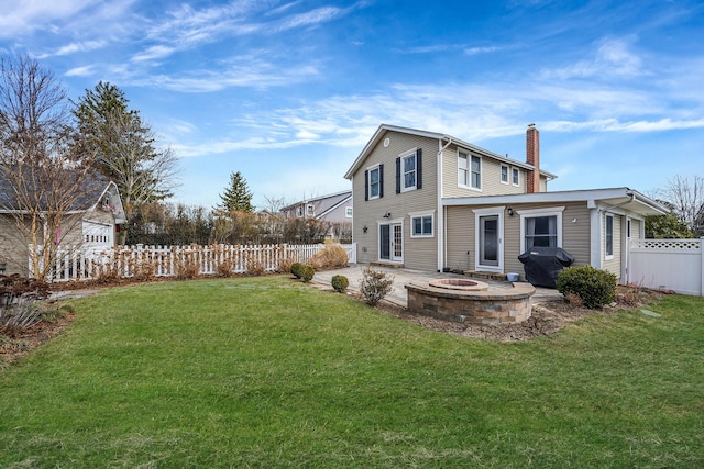 rear view of property with a patio, a fenced backyard, a yard, a fire pit, and a chimney