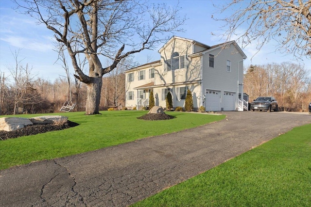 view of front of home featuring driveway, an attached garage, and a front lawn