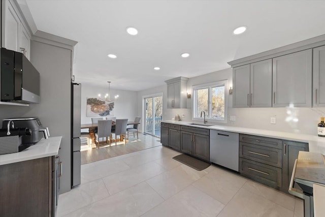 kitchen featuring recessed lighting, gray cabinets, a sink, stainless steel appliances, and light countertops