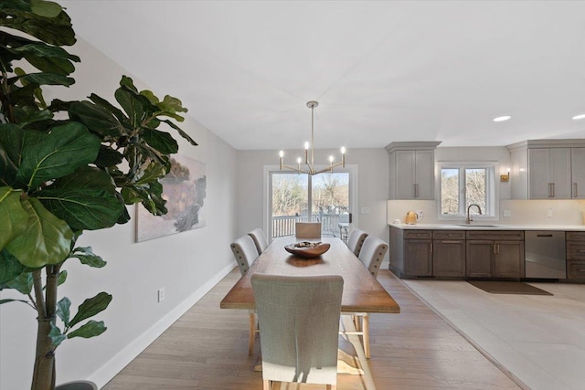 dining space featuring an inviting chandelier, baseboards, and light wood finished floors