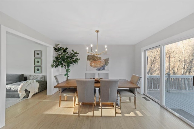 dining area featuring light wood-type flooring, visible vents, and a chandelier