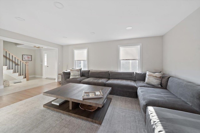 living area featuring stairs, wood finished floors, and baseboards