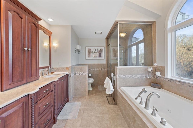 full bath featuring toilet, a stall shower, vanity, tile walls, and a whirlpool tub