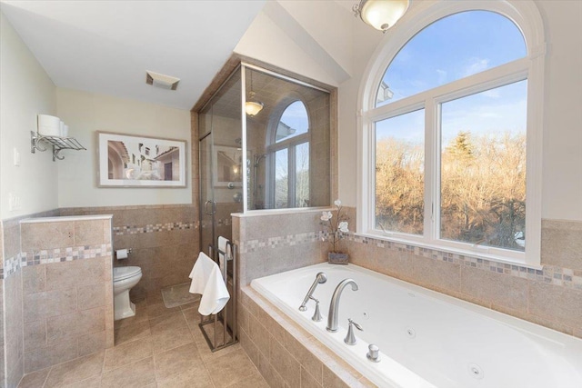 bathroom featuring visible vents, a shower stall, toilet, a tub with jets, and tile walls