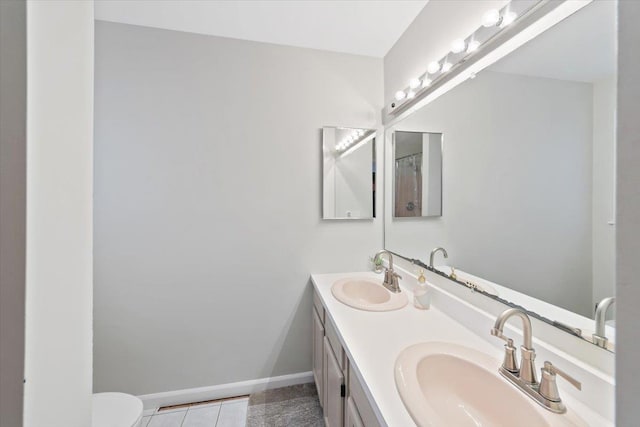 full bath featuring tile patterned flooring, double vanity, baseboards, and a sink