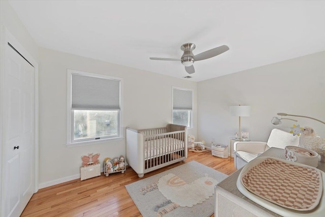 bedroom with a closet, multiple windows, baseboards, and wood finished floors