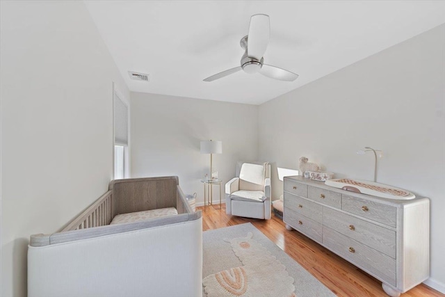 bedroom with baseboards, light wood-style floors, visible vents, and ceiling fan