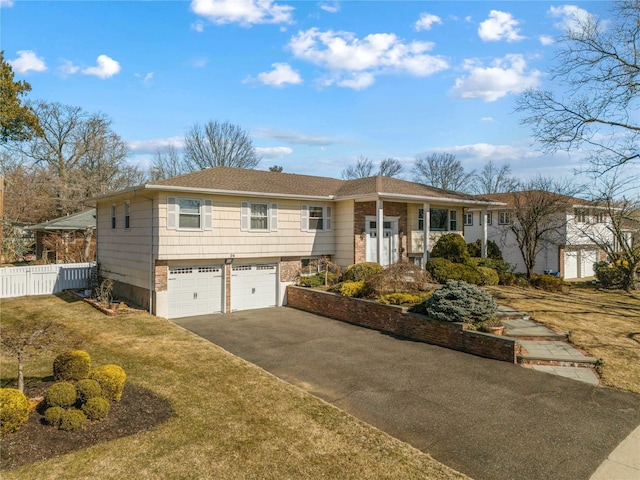 view of front facade with driveway, a front yard, a garage, and fence