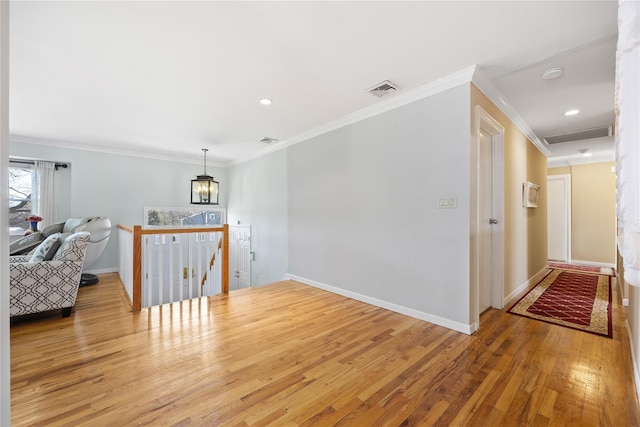 living area with baseboards, wood finished floors, visible vents, and ornamental molding