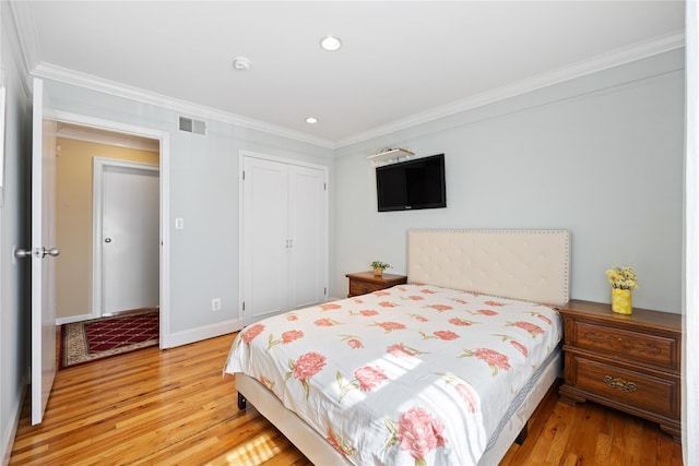 bedroom with visible vents, a closet, light wood-style flooring, and ornamental molding