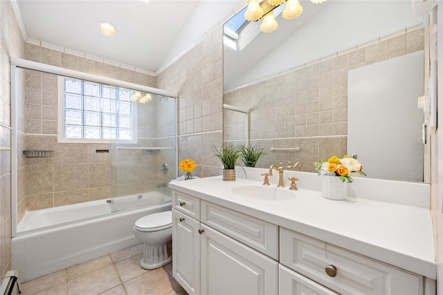 bathroom featuring vanity, lofted ceiling with skylight, a baseboard heating unit, tile walls, and toilet