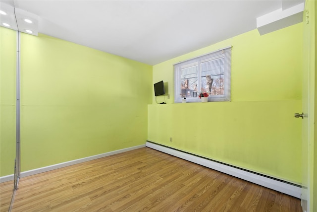 spare room with recessed lighting, wood finished floors, baseboards, and a baseboard radiator