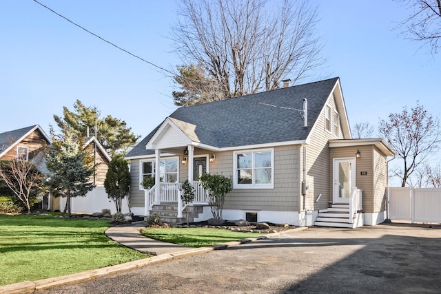 view of front of house with driveway, fence, a front yard, a shingled roof, and a chimney