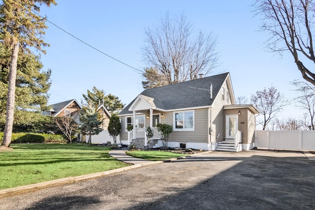 bungalow-style home with driveway, a shingled roof, a front yard, and fence