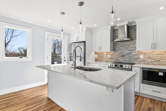 kitchen with a sink, backsplash, stainless steel appliances, wall chimney exhaust hood, and a kitchen island with sink