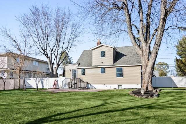 rear view of house with a yard, a chimney, and fence