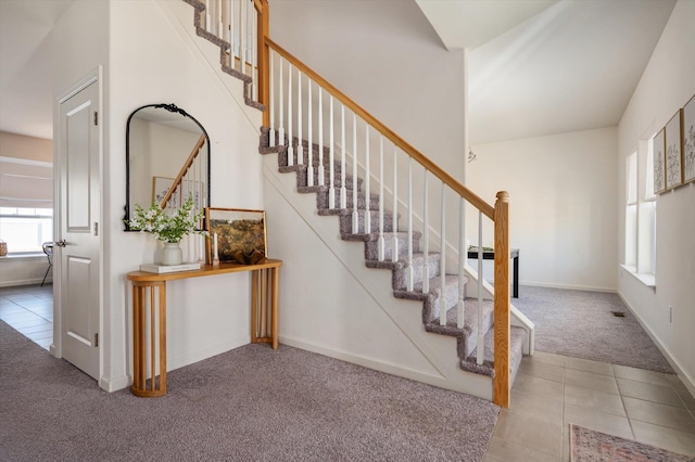 stairway with tile patterned floors, carpet flooring, and baseboards