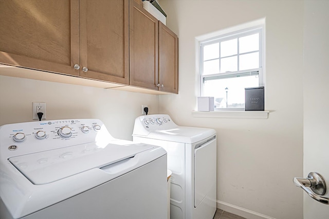 washroom with baseboards, cabinet space, and independent washer and dryer