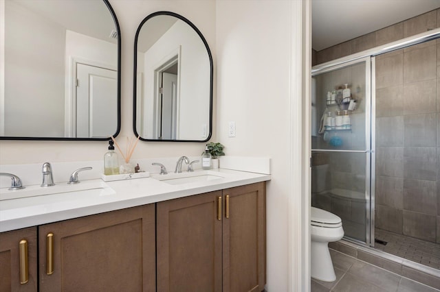 full bathroom with tile patterned floors, a stall shower, toilet, and a sink