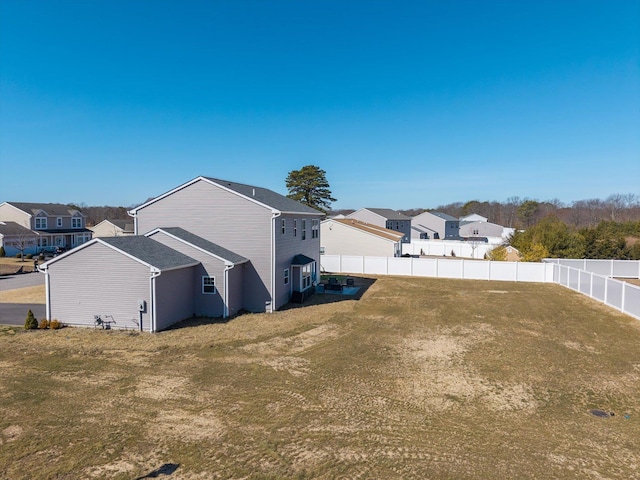 view of side of property featuring a fenced backyard, a residential view, and a yard