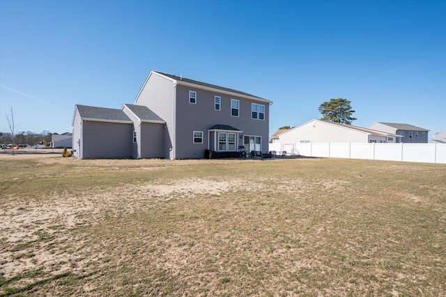 rear view of property with a lawn and fence