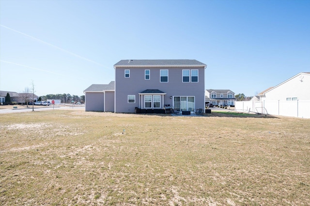 back of house featuring a lawn and fence