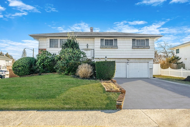 raised ranch featuring aphalt driveway, a garage, a front lawn, and fence