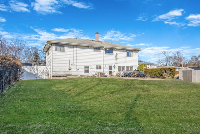 back of house featuring a storage shed, an outbuilding, and a lawn