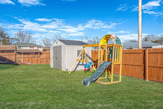 view of jungle gym with an outbuilding, a yard, a fenced backyard, and a shed