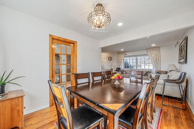 dining room with light wood finished floors, recessed lighting, baseboards, and an inviting chandelier