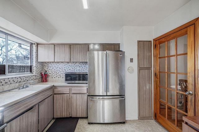 kitchen featuring light countertops, tasteful backsplash, appliances with stainless steel finishes, and a sink