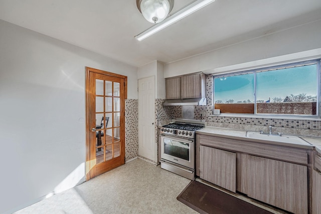 kitchen with decorative backsplash, light countertops, stainless steel gas range, and a sink