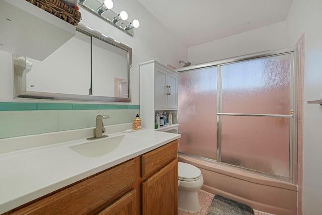 bathroom featuring tile patterned floors, toilet, combined bath / shower with glass door, decorative backsplash, and vanity