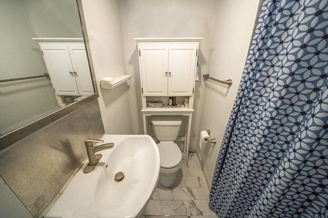 bathroom with a shower with shower curtain, toilet, marble finish floor, and a sink