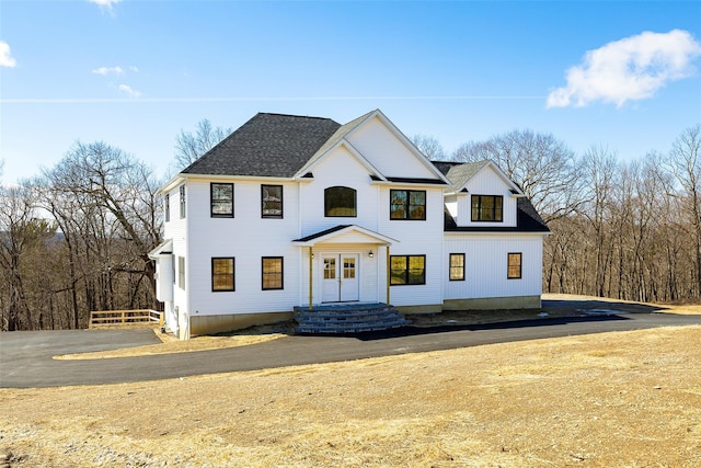 modern inspired farmhouse with fence and a shingled roof