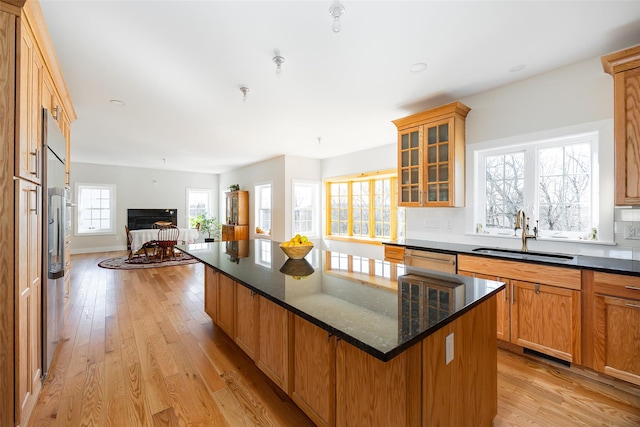 kitchen featuring dishwasher, light wood-style flooring, open floor plan, and a sink