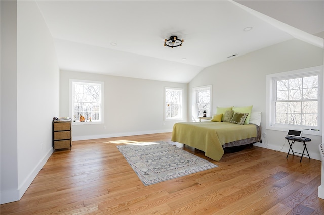 bedroom with visible vents, baseboards, light wood-style floors, and lofted ceiling