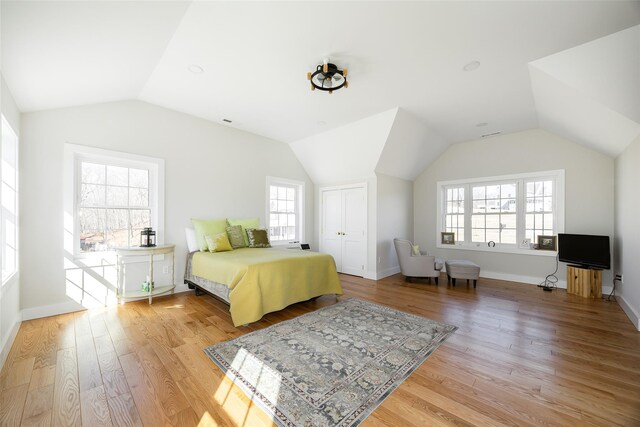 bedroom featuring baseboards, lofted ceiling, light wood-style floors, and a closet