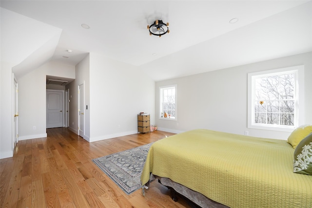 bedroom featuring baseboards, lofted ceiling, and light wood-style floors