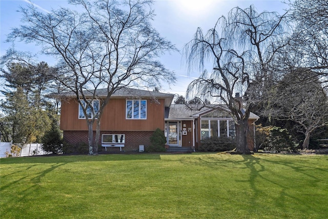 tri-level home with brick siding, a front yard, and fence