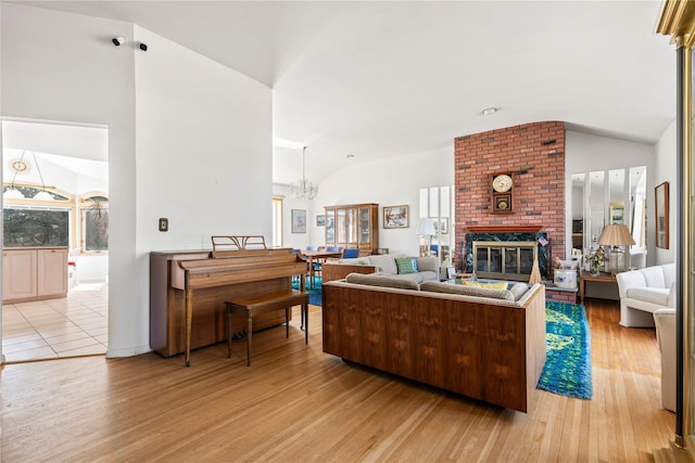 living area with lofted ceiling, a notable chandelier, light wood-style flooring, and a fireplace