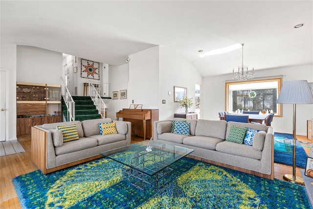 living room featuring an inviting chandelier, wood finished floors, stairs, and vaulted ceiling