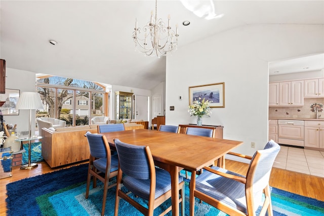 dining space featuring light wood-type flooring, lofted ceiling, and an inviting chandelier