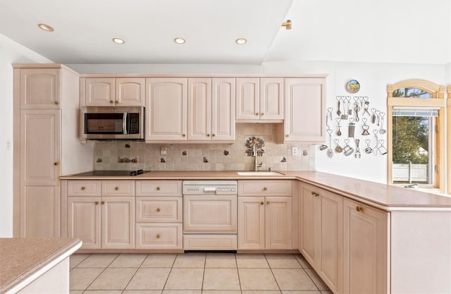 kitchen featuring a sink, stainless steel microwave, a peninsula, light tile patterned floors, and dishwasher