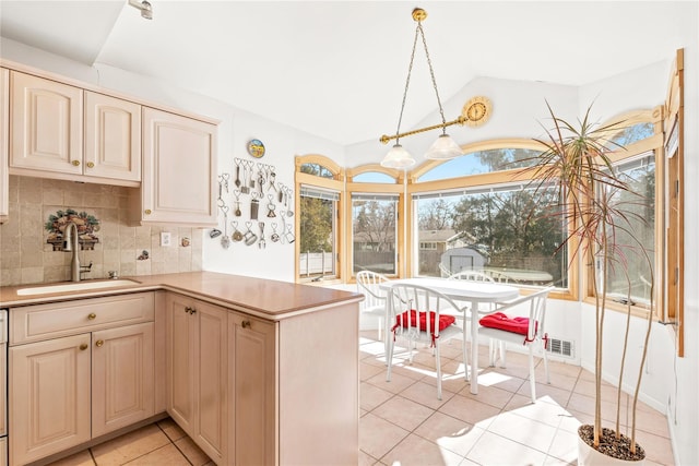 kitchen with visible vents, backsplash, vaulted ceiling, a peninsula, and a sink