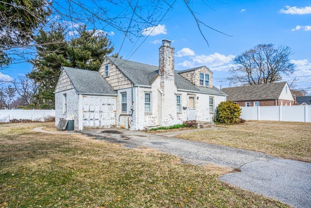 view of front of home with a front lawn, a fenced backyard, roof with shingles, and a chimney