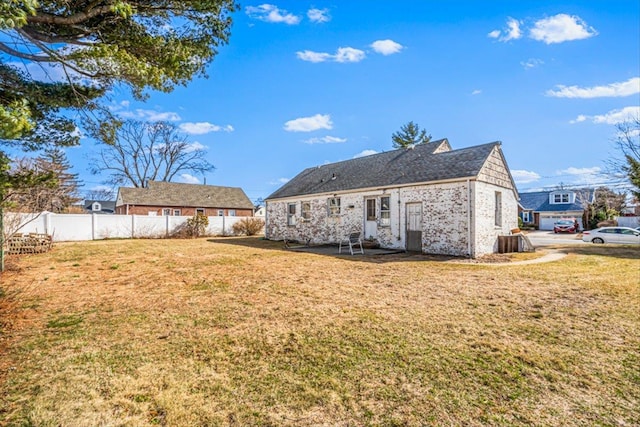 rear view of property featuring a yard and fence