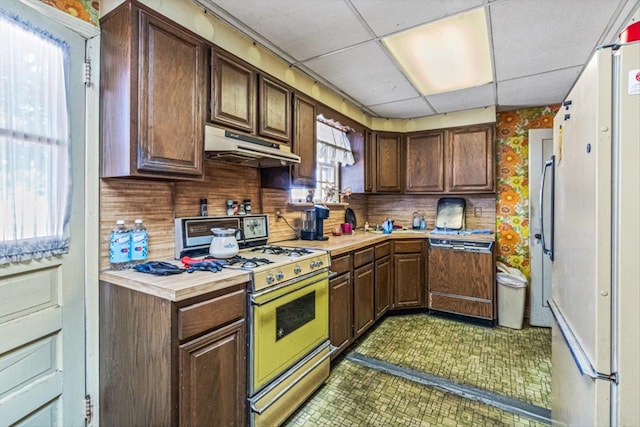 kitchen featuring under cabinet range hood, freestanding refrigerator, gas stove, light countertops, and dishwasher