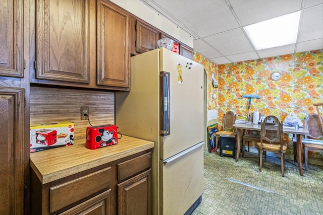 kitchen with wallpapered walls, a paneled ceiling, and freestanding refrigerator